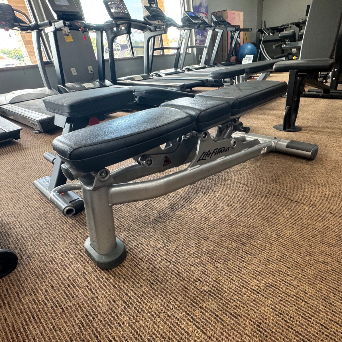 Gym bench in a fitness center with treadmills in the background
