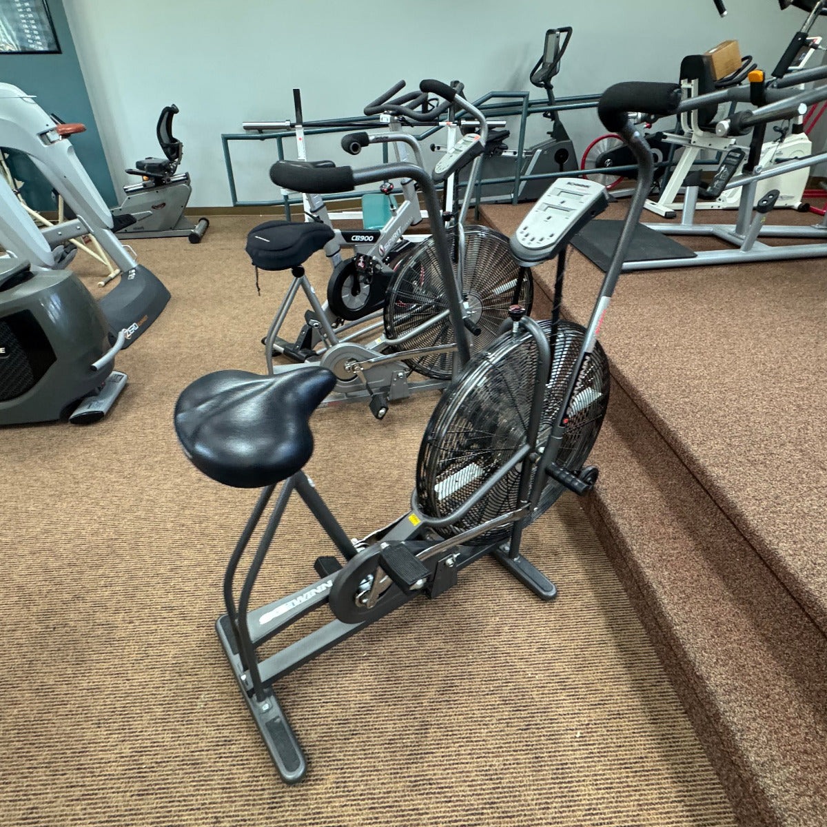 Exercise bike in a gym setting with other equipment in the background