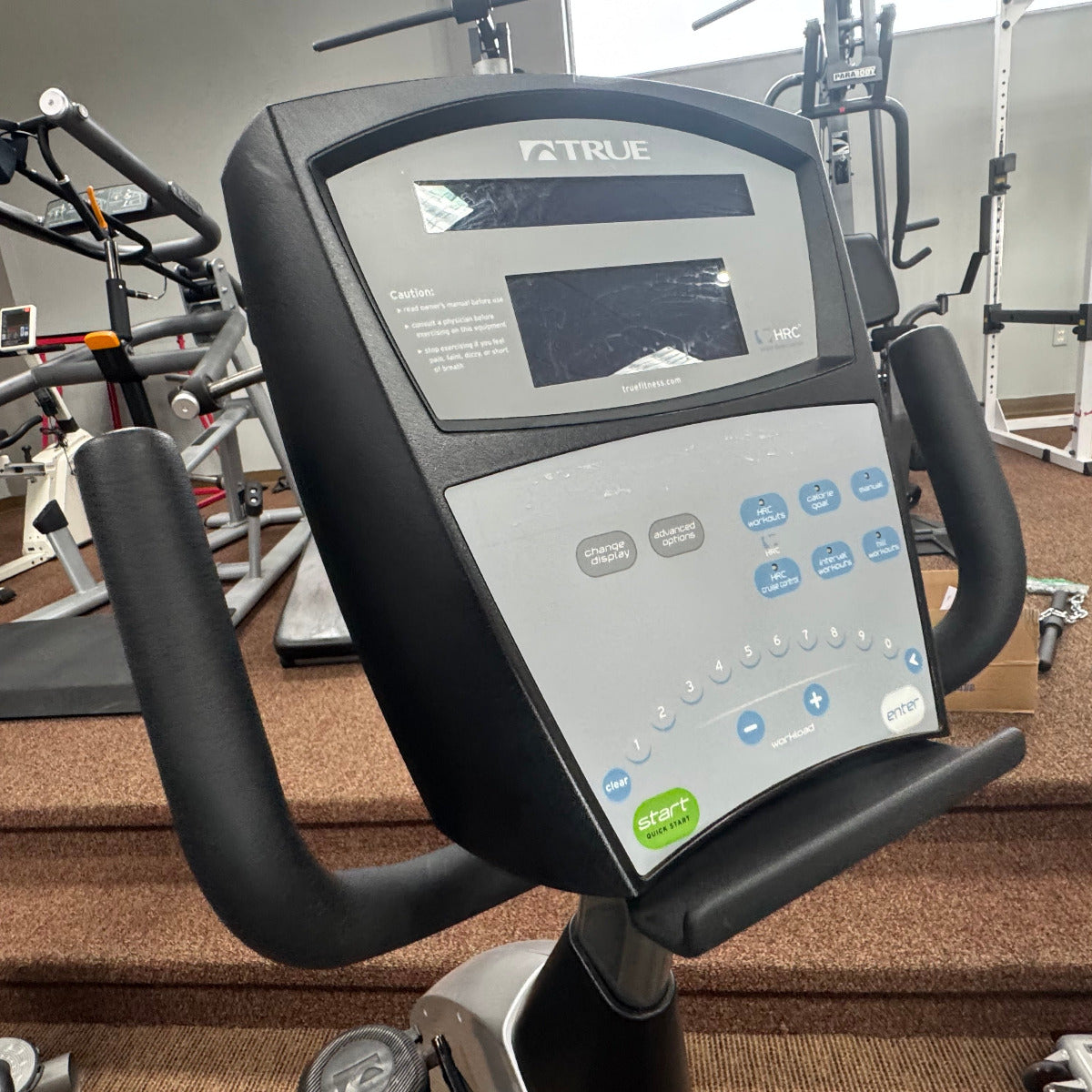 Close-up of a True brand exercise bike console in a gym setting