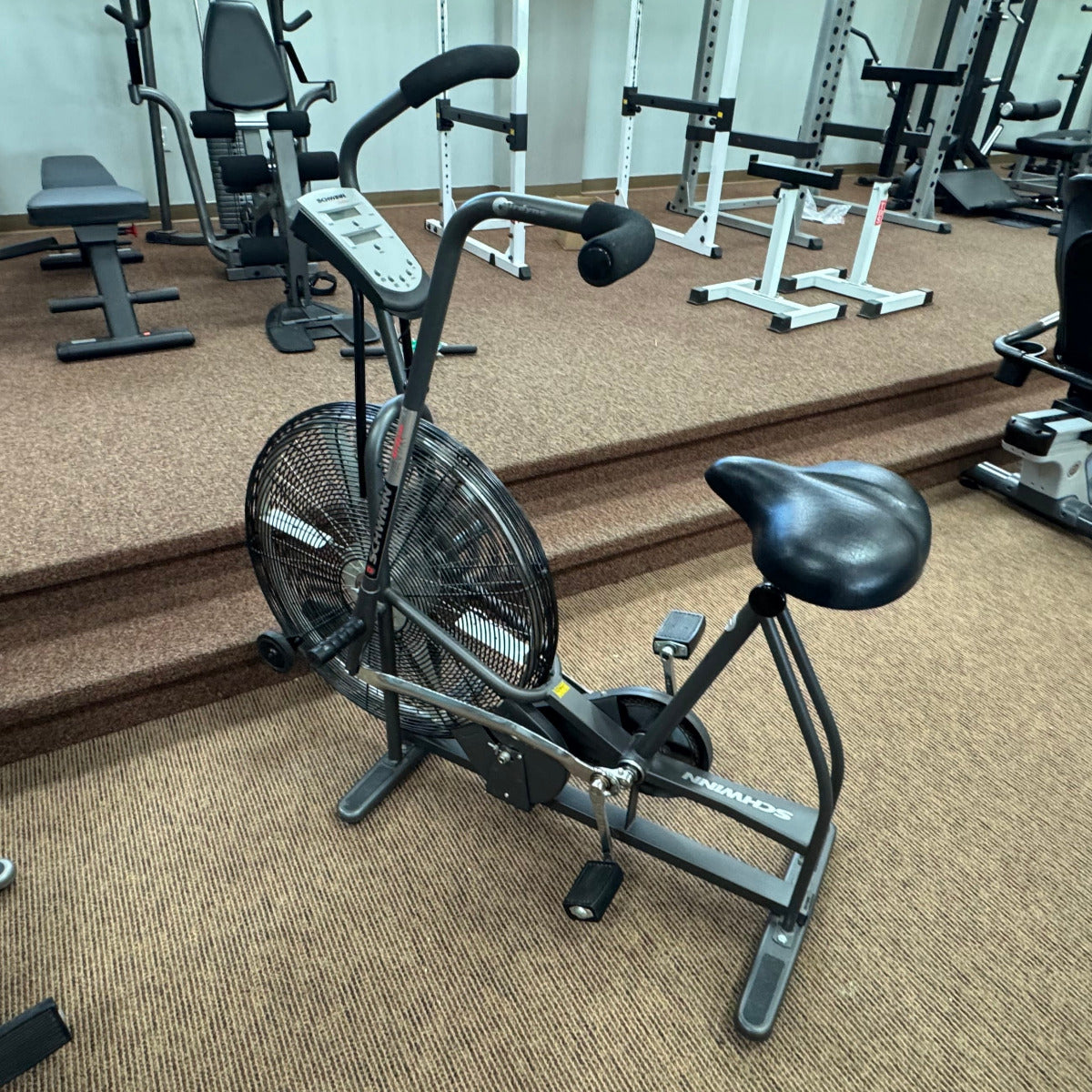 Exercise bike in a gym setting with various equipment in the background