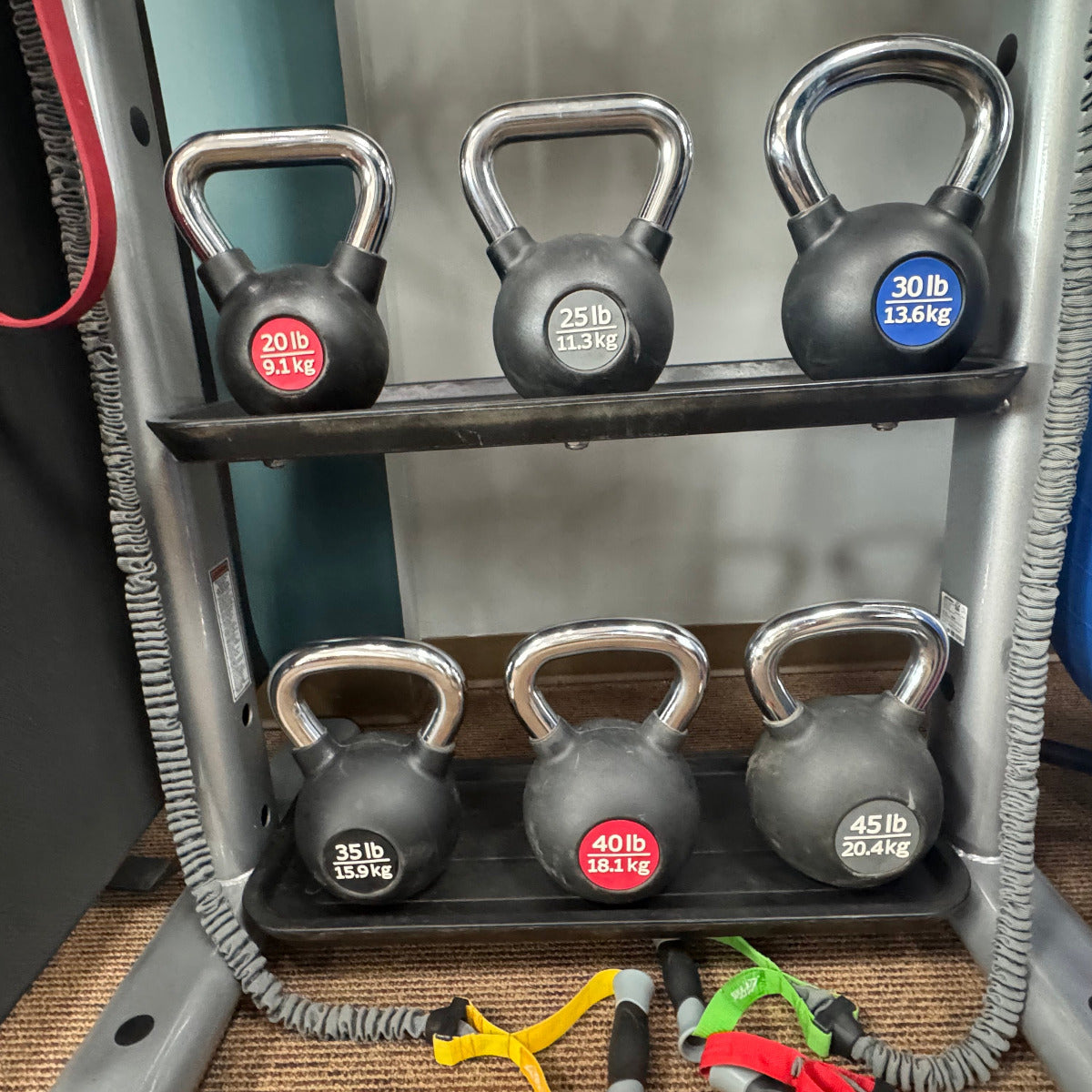 Set of kettlebells on a rack with various weights in a gym setting