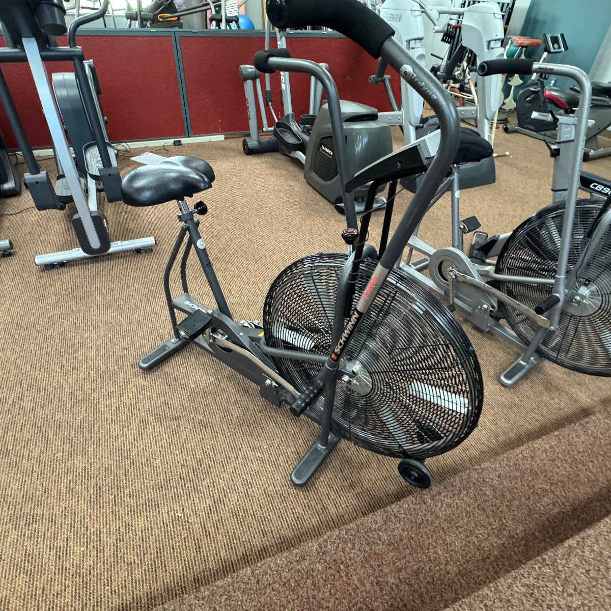 Exercise bike in a gym setting with other equipment in the background