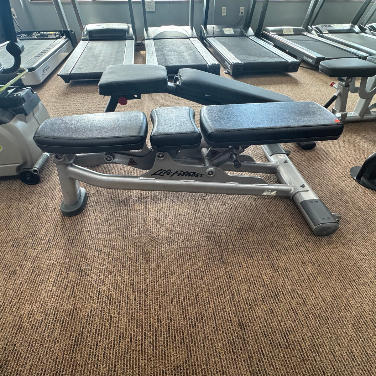 Gym bench in a fitness center with treadmills in the background