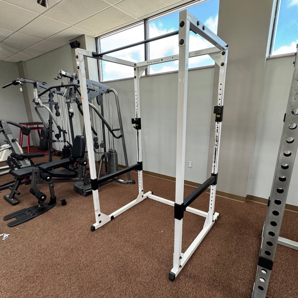 Gym interior with weight lifting equipment including a power rack.