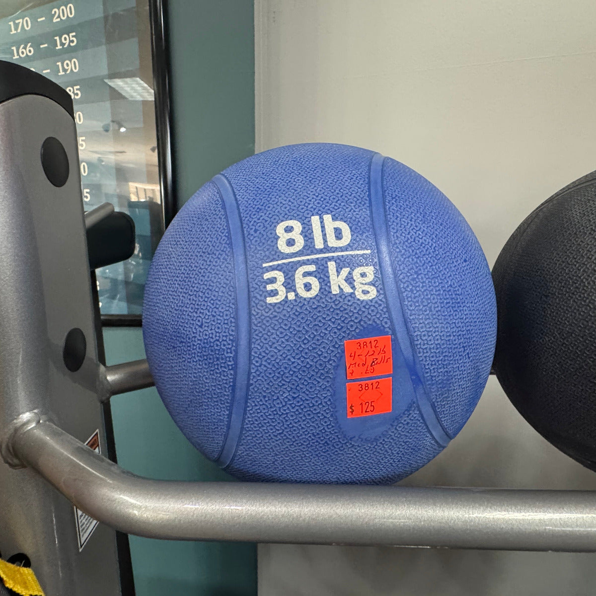 Blue medicine ball labeled '8 lb 3.6 kg' on a gym machine.