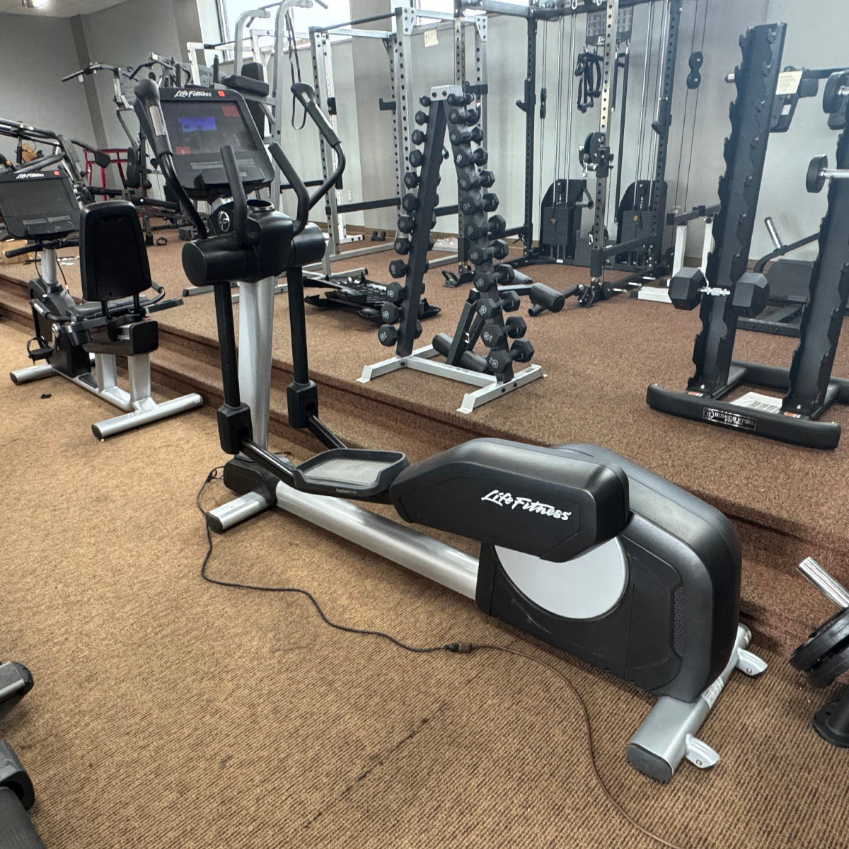 Gym interior with cardio equipment and weight machines.