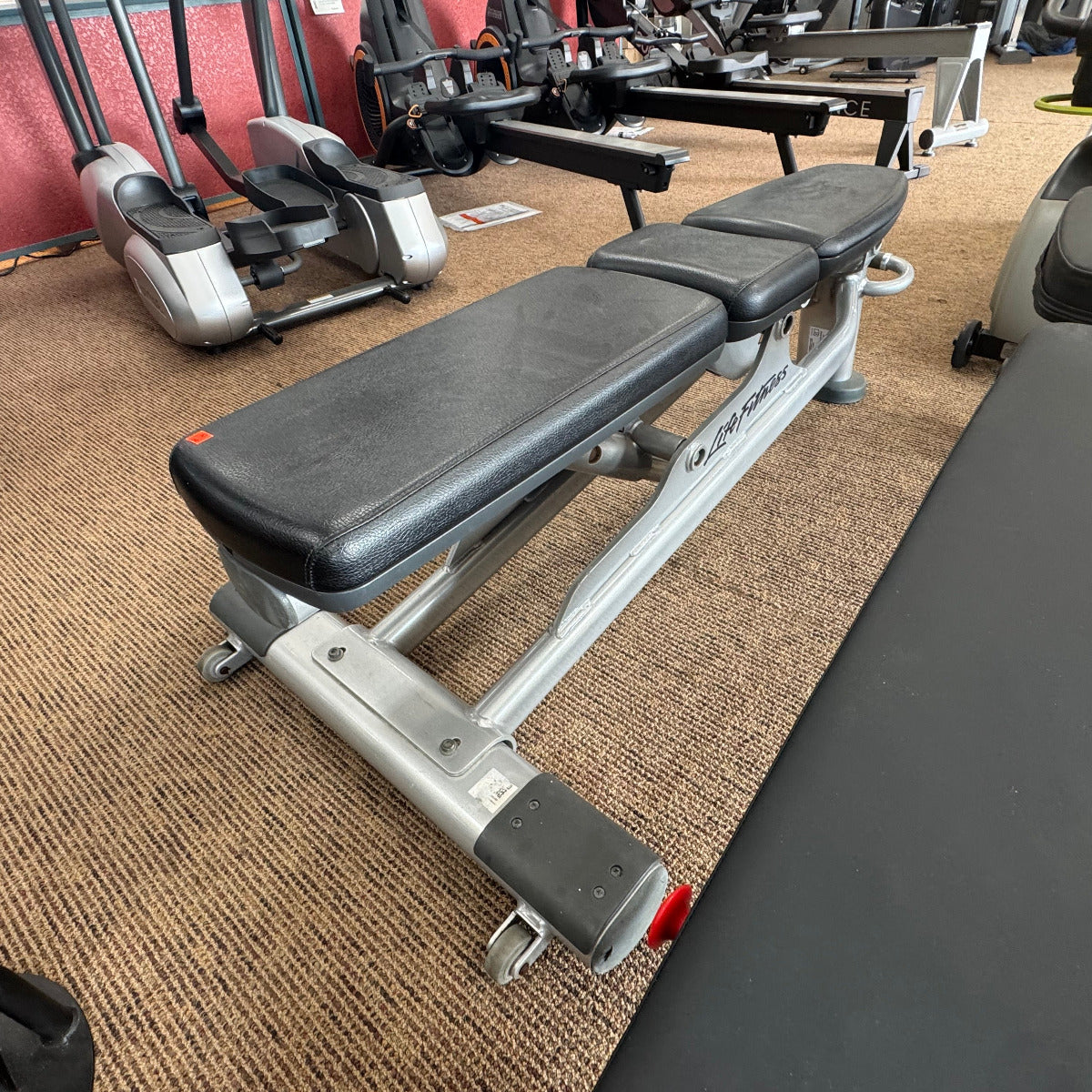 Gym bench in a fitness center with equipment in the background