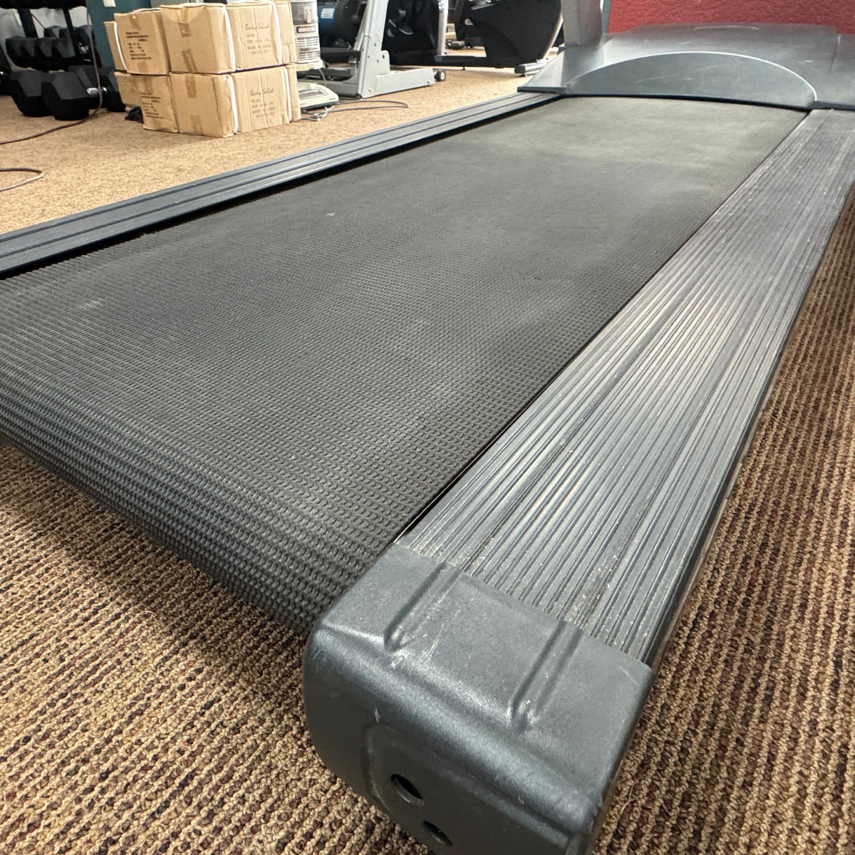 Gray treadmill on a carpeted floor with boxes in the background