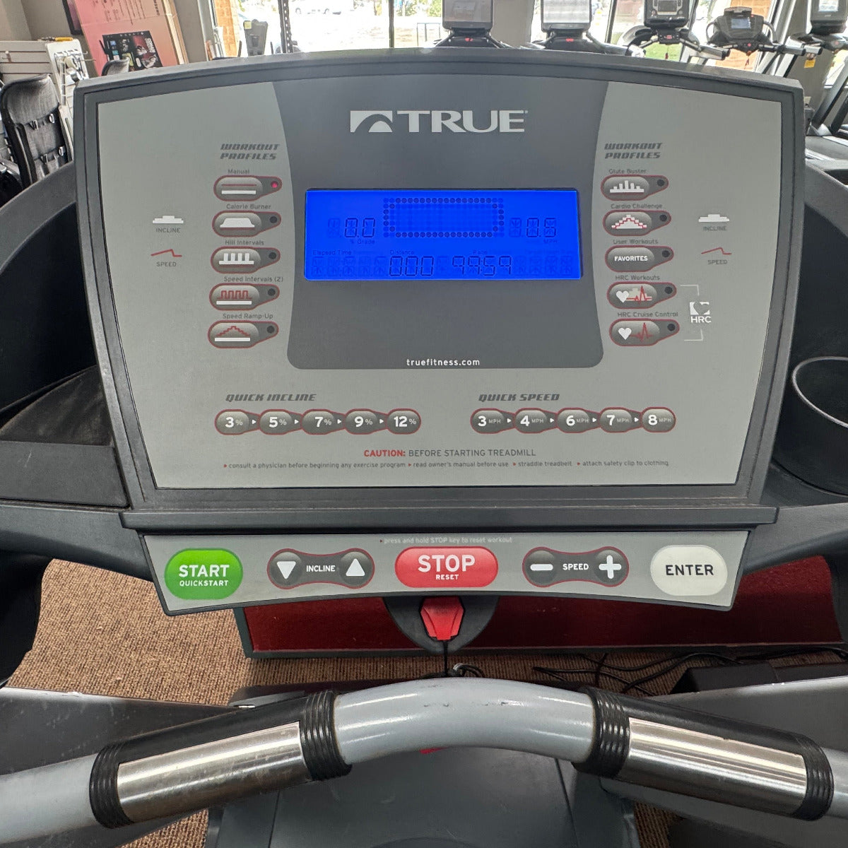 Control panel of a True brand treadmill with digital display and buttons.