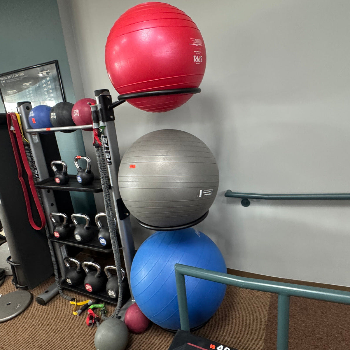 Gym equipment including exercise balls and weights in a room.
